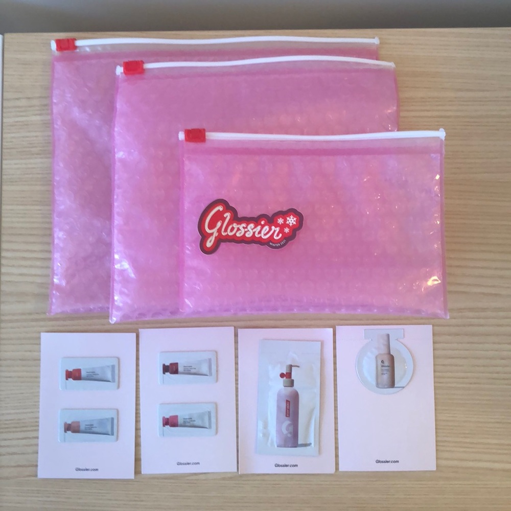 3 Glossier pink pouches, 4 samples, and 1 sticker